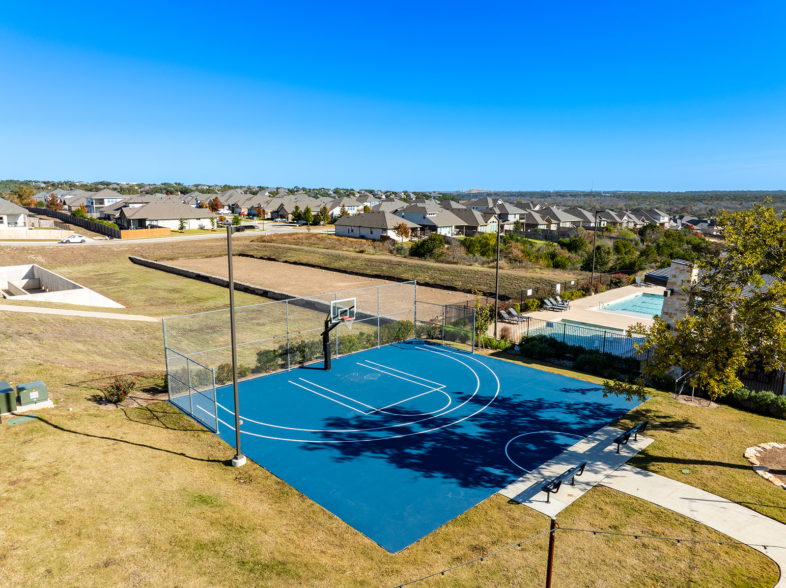 Community basketball court with pool and Hill Country views at Water Oak at San Gabriel