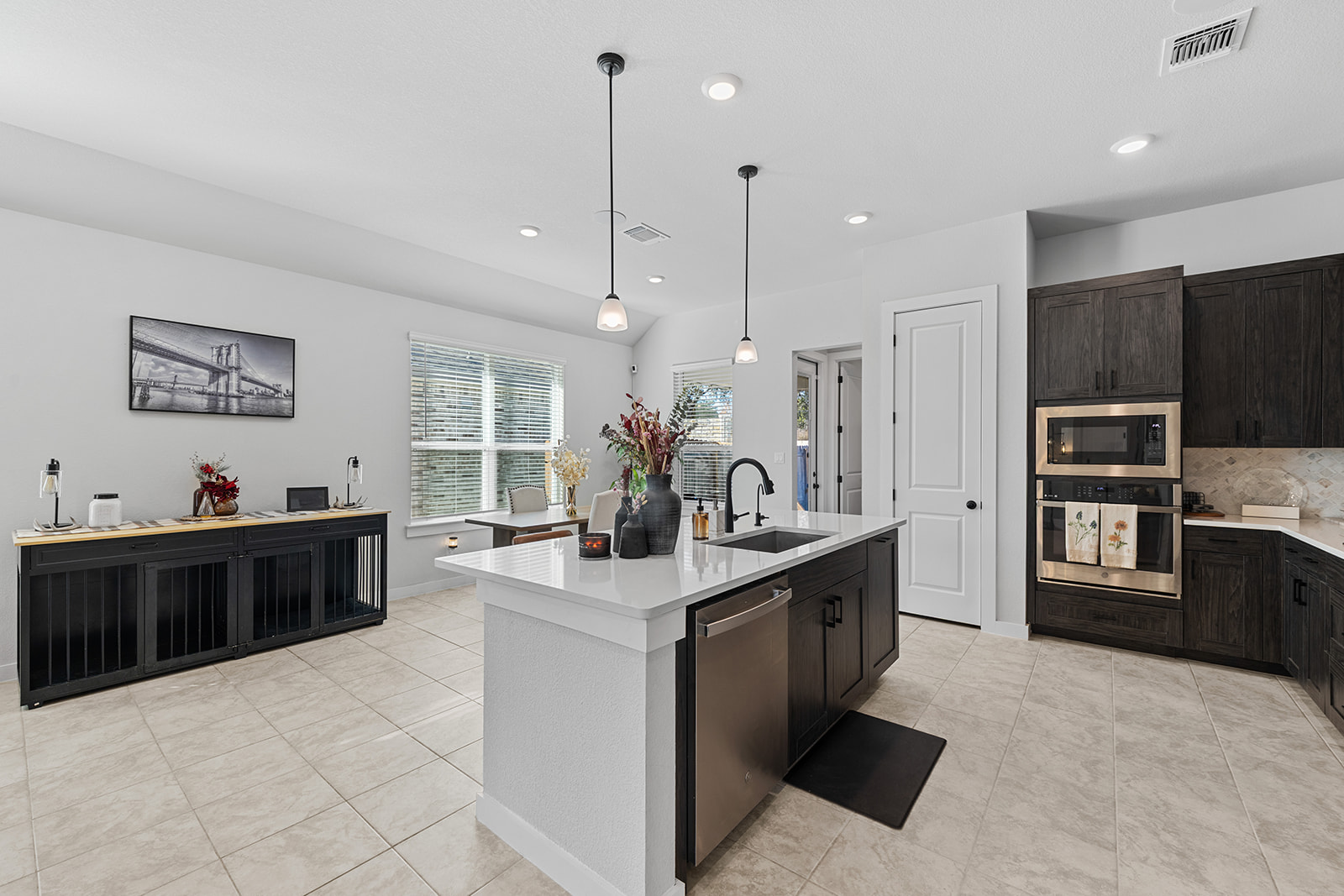 Kitchen island with built-in oven, microwave, dark cabinets and open floor plan to dining