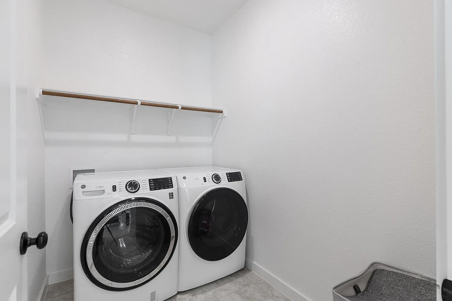Laundry room with GE front-load washer and dryer, shelf with hanging rod