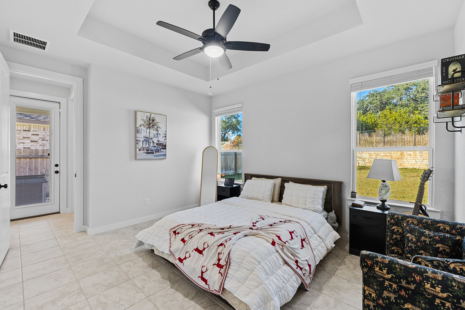 Primary bedroom alternate angle — tray ceiling, en-suite bath entry, backyard views and ceiling fan